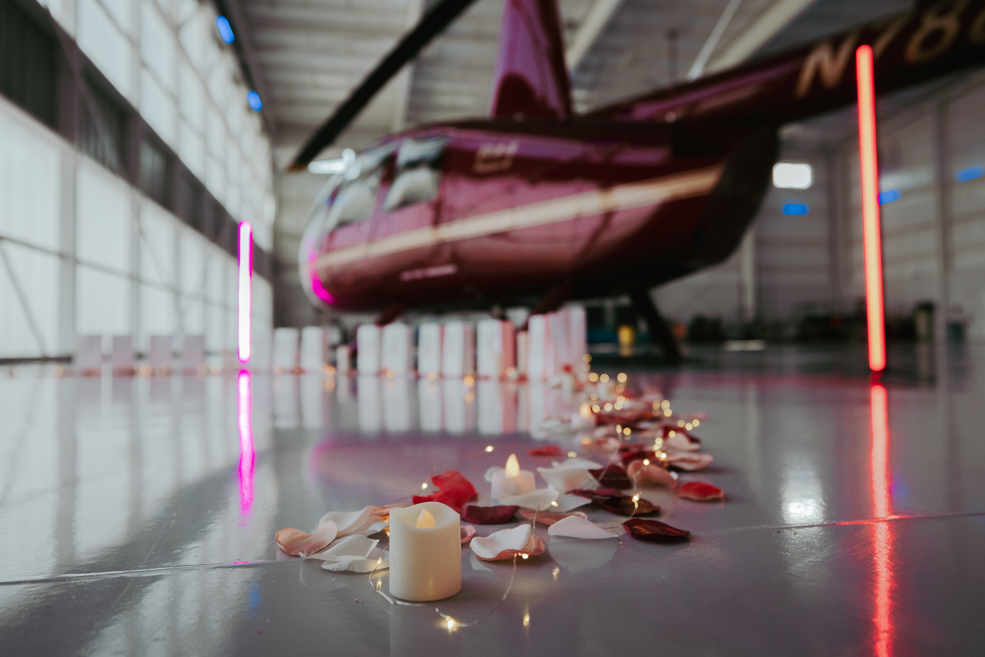 Rose petals, candles, and lights leading to a helicopter proposal setup in the hangar