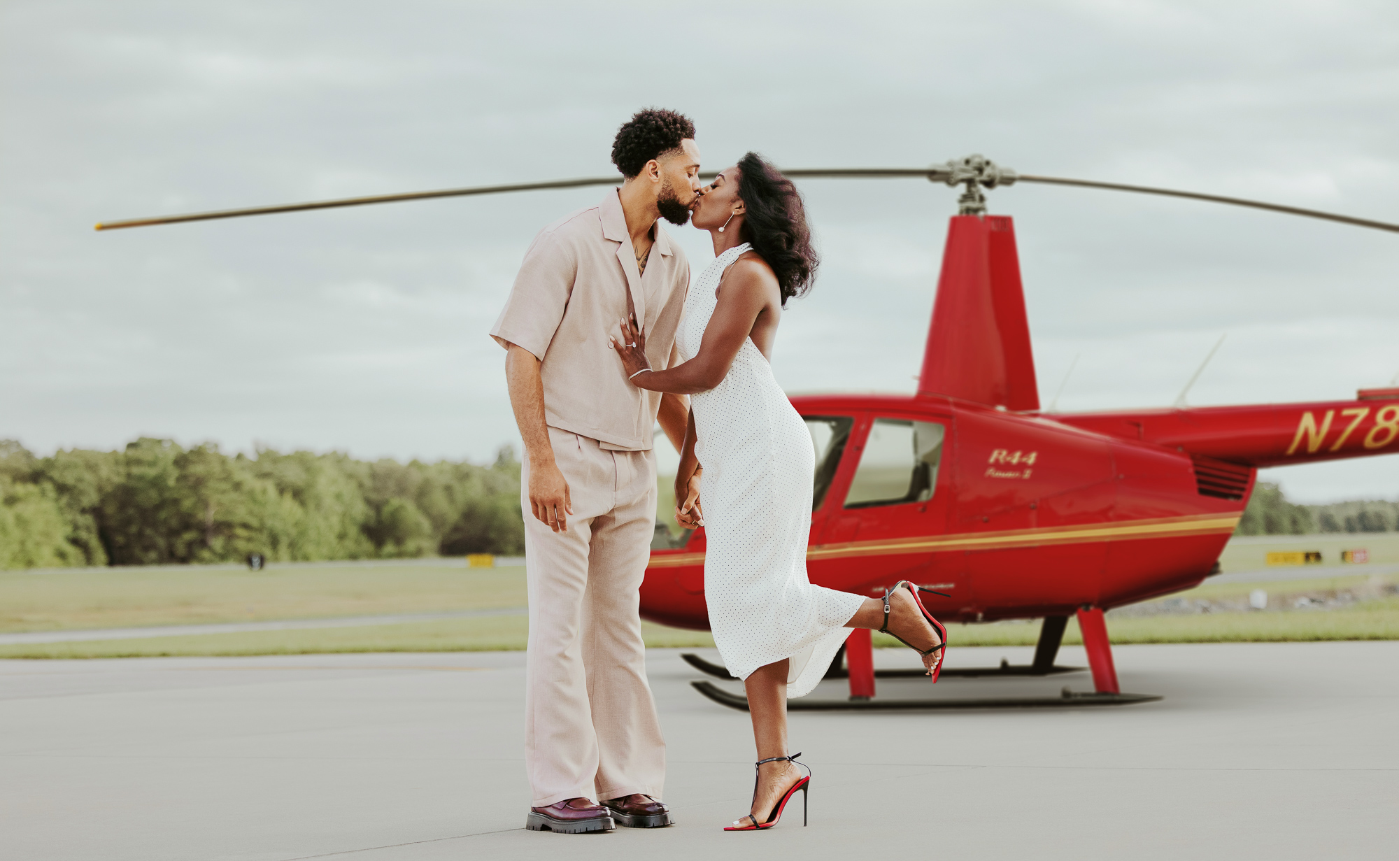 Couple kissing on the tarmac in front of a Charlotte Helicopters R44